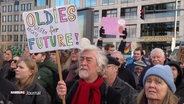 Demonstranten in der Hamburger Innenstadt, ein älterer Mann mit einem bunten Schild: "Oldies for future / Oldies gegen Rechts". © Screenshot 