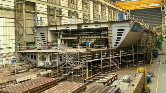 Ein noch nicht fertig gebautes Schiff in einer Werft. © Screenshot 