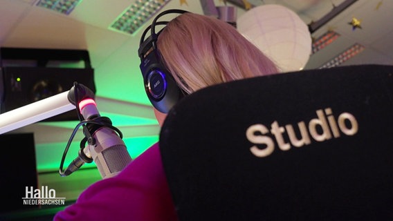 "Studio" steht auf der Stuhllehne der Radio-Moderatorin. © Screenshot 