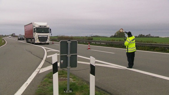 Ein Polizist hält ein Auto zur Verkehrskontrolle an. © Screenshot 