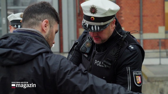 Ein Polizeibeamter kontrolliert einen Passanten auf illegale Waffen. © Screenshot 