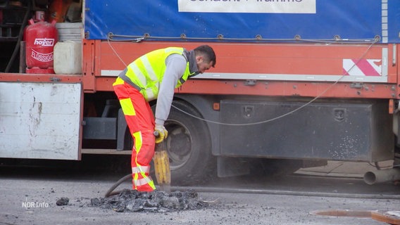 Ein Bauarbeiter arbeitet mit einem Presslufthammer an einer Straße. © Screenshot 