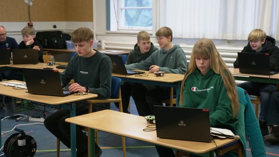 jugendliche sitzen in einem Klassenzimmer und schauen auf Laptops. © Screenshot 