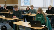 jugendliche sitzen in einem Klassenzimmer und schauen auf Laptops. © Screenshot 