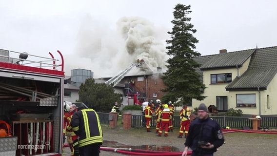 Feuerwehrleute bei einem Einsatz vor einem stark qualmenden Haus in einer Wohnsiedlung © Screenshot 