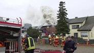 Feuerwehrleute bei einem Einsatz vor einem stark qualmenden Haus in einer Wohnsiedlung © Screenshot 