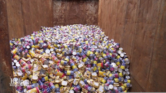 In einem Container liegen tausende Tierfutterdosen in einem Haufen. © Screenshot 