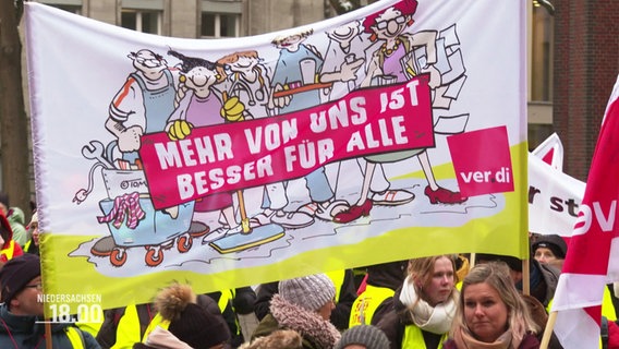 Demonstrierende mit einem Banner mit der Aufschrift: "Mehr von uns ist besser für alle". © Screenshot 