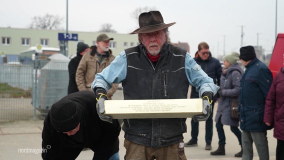 Künstler Gunther Demnig hält die Stolperschwelle für Pasewalk. © Screenshot 