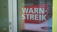 Ein Plakat hinter einer Tür mit der Aufschrift: "Heute Warnstreik". © Screenshot 