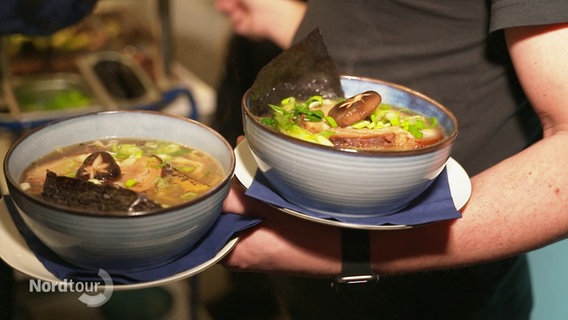 Ein Kellner serviert zwei Ramen-Schüsseln. © Screenshot 