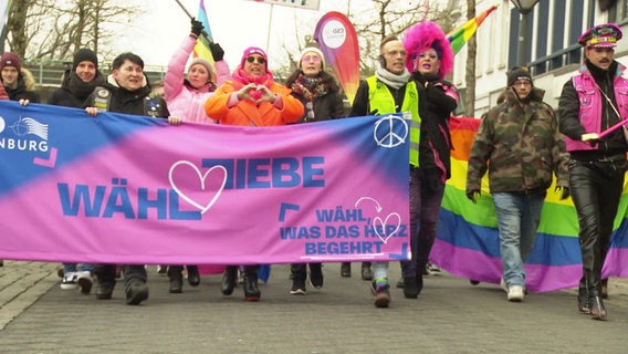 Demonstrierende hinter einem Banner mit der Aufschrift "Wähl Liebe". © Screenshot 