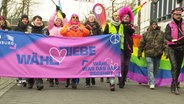 Demonstrierende hinter einem Banner mit der Aufschrift "Wähl Liebe". © Screenshot 