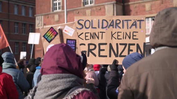 Ein Plakat auf einer Demo. Es trägt die Aufschrift: "Solidarität kennt keine Grenzen". © Screenshot 