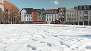 Eine Schneefläche im Vordergrund, Bänke und Häuser im HIntergrund aus der Froschperspektive. © Screenshot 