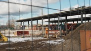 Blick durch einen Baustellenzaun: Eine Baustelle an einem Bahnhof. © Screenshot 