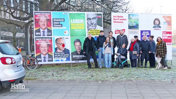 Eine Familie posiert für ein Foto vor Wahlplakaten. © Screenshot 