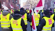 Demonstrierende in gelben Warnwesten mit Flaggen der Gewerkschaft ver.di. © Screenshot 