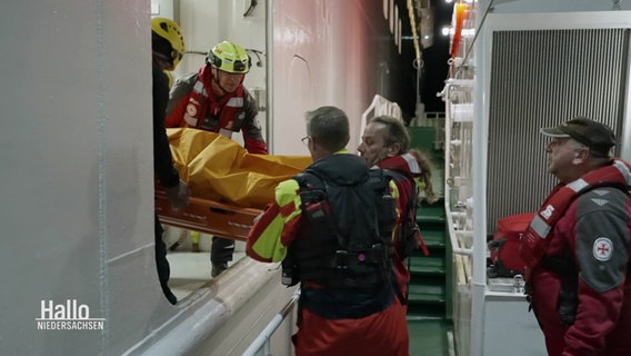 Eine Krankenbare wird von einem Kreuzfahrtschiff auf einen Seenotrettungskreuzer übergeben. © Screenshot 