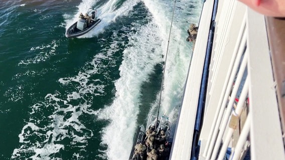 Der Blick vom Deck einer Fähre herunter auf ein Schlauchboot der Polizei. Spezialkräfte üben, auf das fahrende Schiff zu steigen. © Screenshot 