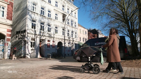 Ein junges Paar geht mit einem Kinderwagen spazieren. © Screenshot 