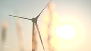 Eine Windkraftanlage steht im Vordergrund eines Sonnenuntergangs. © Screenshot 