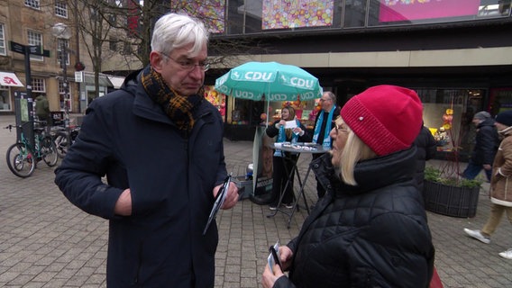 Mathias Middelberg (CDU) spricht mit einer Frau. © Screenshot 