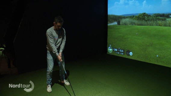 Ein Mann spielt Indoor Golf und steht vor der Landschaftsprojektion. © Screenshot 