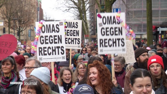 Eine große Demonstration mit Schildern „OMAS GEGEN RECHTS“, bunt geschmückt. Menschen lachen und marschieren gemeinsam. © Screenshot 