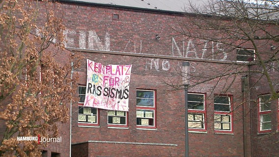 Ein Banner mit der Aufschrift "Kein Platz für Rassismus" hängt an einer Fassade. © Screenshot 