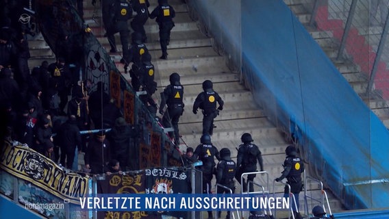 Bei einem Fußballspiel stürmen Polizeikräfte in Schutzausrüstung eine Fantribüne. © Screenshot 