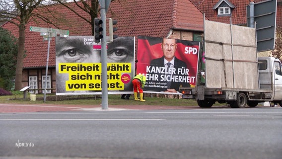 An einer Straße werden Wahlplakate abgebaut und auf einen Transporter geladen. © Screenshot 