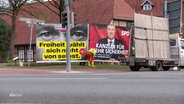 An einer Straße werden Wahlplakate abgebaut und auf einen Transporter geladen. © Screenshot 