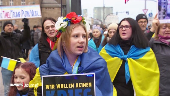 Menschen mit Flaggen und Transparenten demonstrieren gegen den Krieg in der Ukraine. © Screenshot 