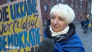 Eine Frau nimmt an einer Solidaritätskundgebung für die Ukraine teil. © Screenshot 