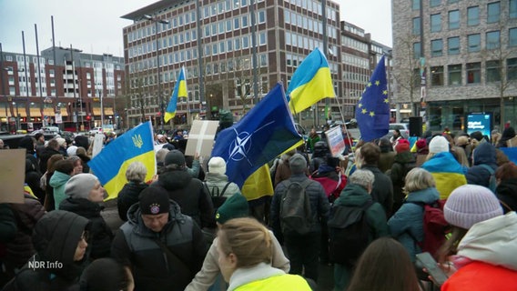 Auf einer Demonstration sind Ukraine- und NATO-Flaggen zu sehen. © Screenshot 