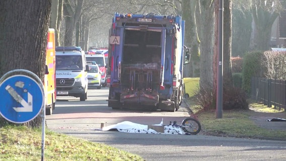 Das Fahrrad eines verunglückten Jungen liegt auf einer Straße. Dahinter ein Müllwagen. © Screenshot 