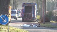 Das Fahrrad eines verunglückten Jungen liegt auf einer Straße. Dahinter ein Müllwagen. © Screenshot 