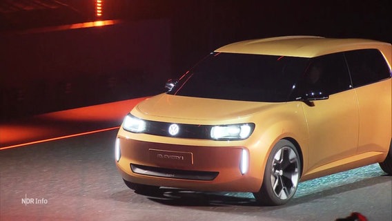 Das neue E-Auto Every1 von VW fährt bei einer Produktvorstellung in eine Halle ein. © Screenshot 