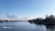 Im blauen Himmel über der Alster steigt eine dunkle Rauchsäule auf. © Screenshot 