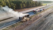 Einsatzkräfte der Feuerwehr löschen einen ausgebrannten Lkw. © Screenshot 