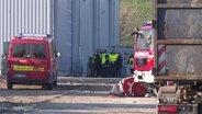 Einsatzkräfte der Feuerwehr stehen auf dem Gelände einer Mülldeponie. © Screenshot 