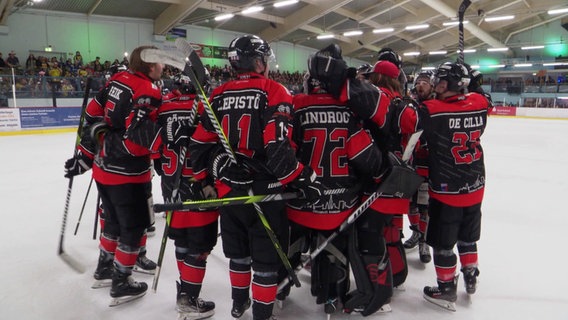 Die Eishockey-Spieler der Crocodiles Hamburg umarmen sich auf dem Eis. © Screenshot 