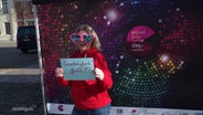 Eine Frau mit Herzsonnenbrille und einem Schild mit der Aufschrift "Gerechtigkeit Jetzt!" auf dem equal pay day in Boizenburg. © Screenshot 