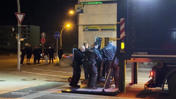 Polizisten laden einen Spielautomaten in einen Lastwagen. © Screenshot 