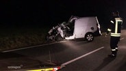 Ein zerstörter Wagen steht am Straßenrand, ein Polizist steht daneben. © Screenshot 