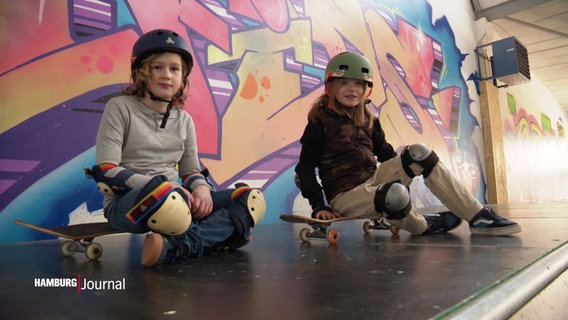 Zwei Kinder sitzen auf Skateboards. © Screenshot 