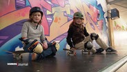 Zwei Kinder sitzen auf Skateboards. © Screenshot 