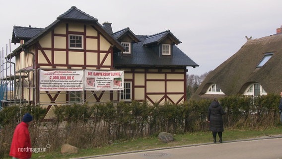 Ein Haus mit einem Gerüst und einem Plakat. © Screenshot 