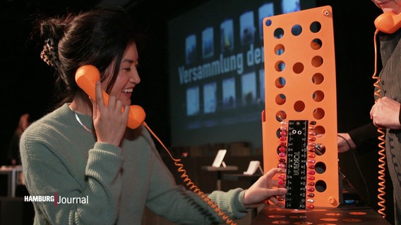 Annette Yang hält einen alten Telefonhörer in der Hand. © Screenshot 